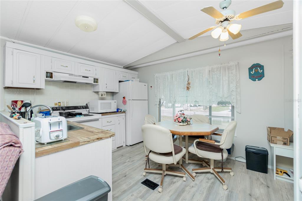 A kitchen and dining area with white cabinets, a ceiling fan, and light wood-look flooring — 7369 CANDACE LANE, PORT CHARLOTTE, FL