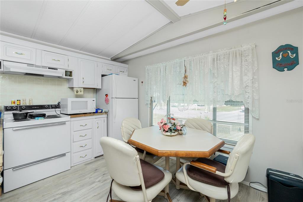 A kitchen with white cabinets, a white stove, a refrigerator, and a dining table — 7369 CANDACE LANE, PORT CHARLOTTE, FL
