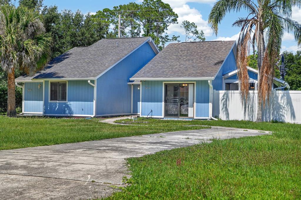A blue duplex with a concrete driveway, a palm tree, and a white privacy fence — 58 BRADMORE LANE UNIT A, PALM COAST, FL
