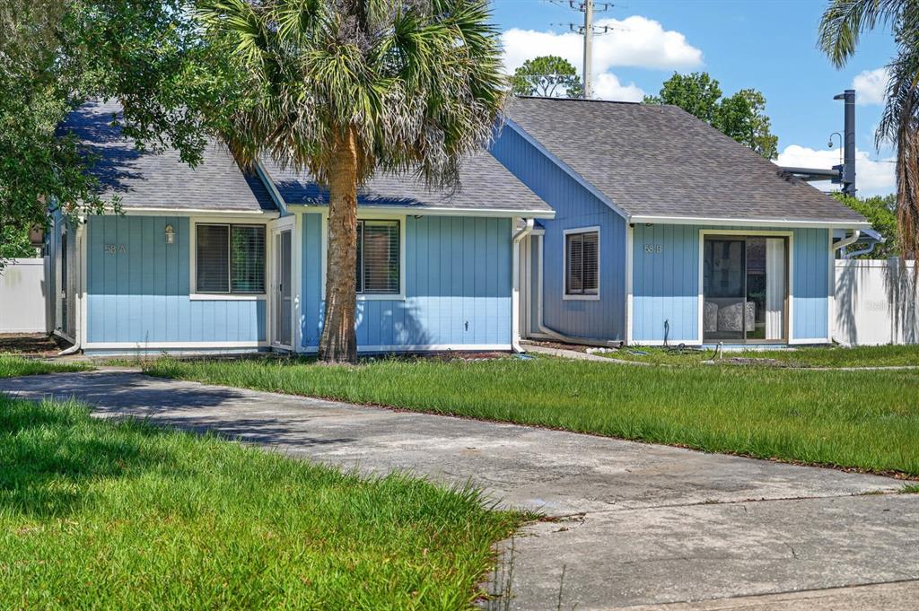 A blue duplex with a concrete driveway, a palm tree, and a grassy front yard — 58 BRADMORE LANE UNIT A, PALM COAST, FL