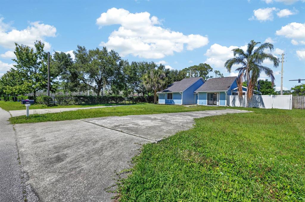 A blue house with a large concrete driveway sits on a grassy lot with trees — 58 BRADMORE LANE UNIT A, PALM COAST, FL