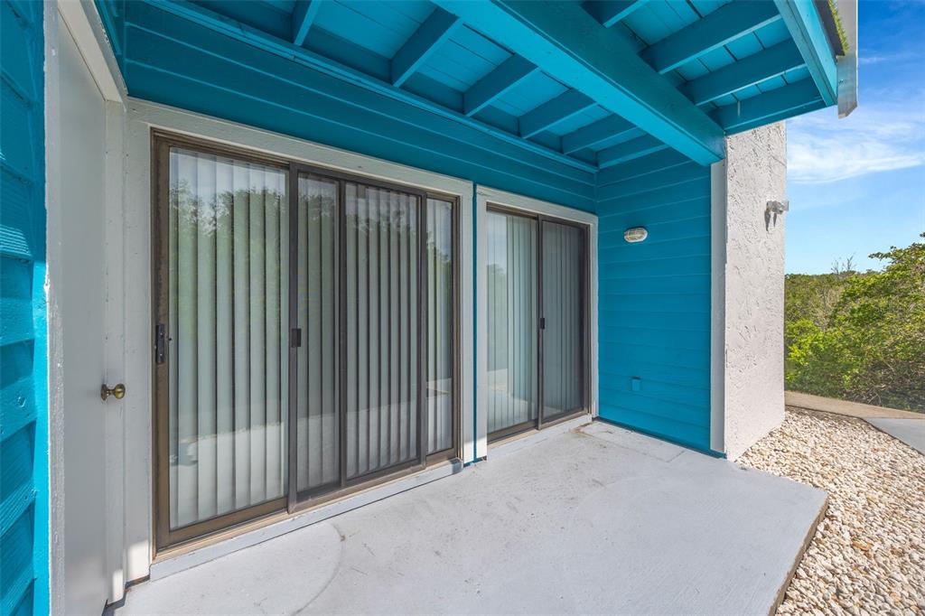 A concrete patio features two sliding glass doors against a bright blue exterior wall — 455 ALT 19 S UNIT 159, PALM HARBOR, FL