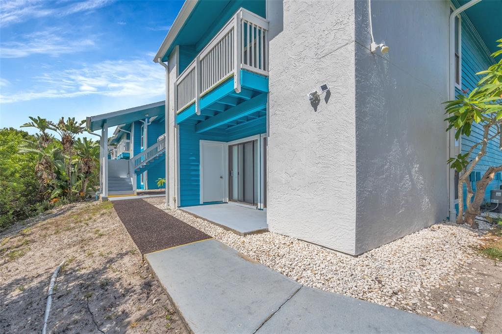 A two-story blue building with a concrete walkway and a ground-level patio — 455 ALT 19 S UNIT 159, PALM HARBOR, FL