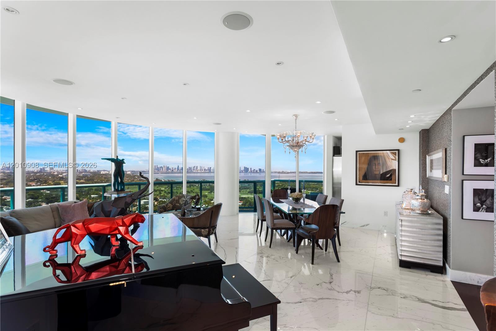 A modern living and dining area features floor-to-ceiling windows, marble floors, and a grand piano — 6000 Indian Creek Dr # 3, Miami Beach FL 33140, MIAMI BEACH, FL