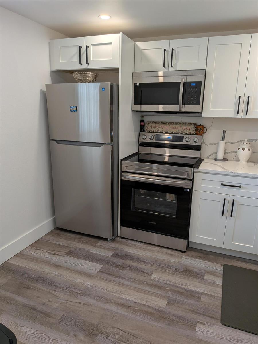 A kitchen features white cabinets, stainless steel appliances, and wood-look flooring — 2601 NE 3rd Court # 2100, Boynton Beach FL 33435, BOYNTON BEACH, FL