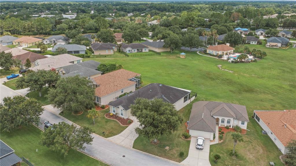 An aerial view shows several suburban houses situated around a large, open grassy field — 5030 SW 63RD LOOP, OCALA, FL