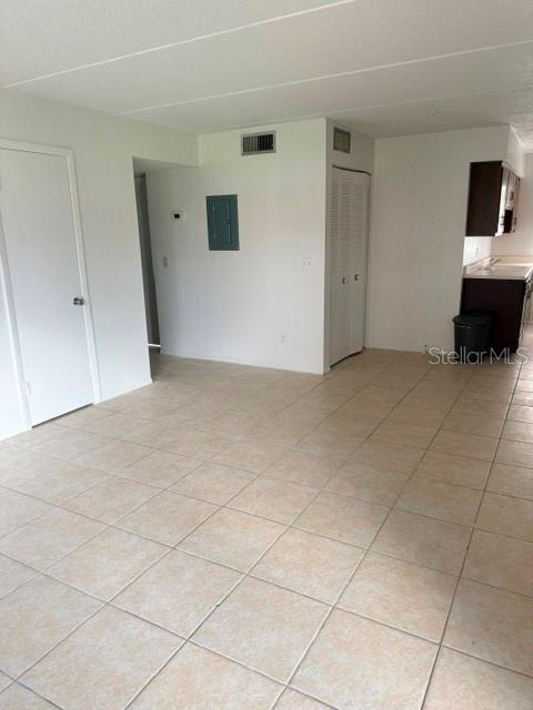 An interior view shows a room with beige tile flooring, white walls, and a kitchen area — 1100 E CAROLINE STREET UNIT 119, TAVARES, FL