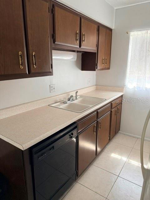 A kitchen features dark wood cabinets, a double sink, a dishwasher, and light-colored countertops — 1100 E CAROLINE STREET UNIT 119, TAVARES, FL