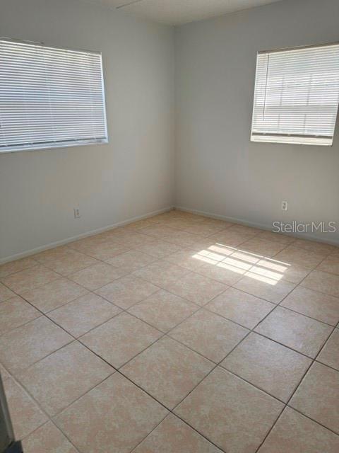An empty room with light-colored walls, tiled flooring, and two windows with horizontal blinds — 1100 E CAROLINE STREET UNIT 119, TAVARES, FL