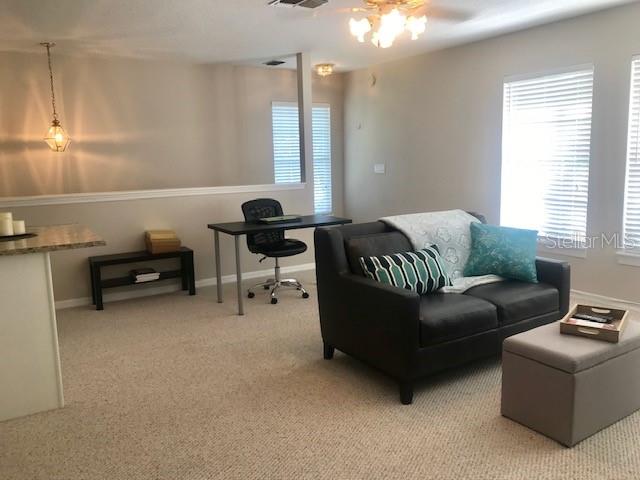 A living room features a dark sofa, a desk with a chair, and beige carpeting — 533 GREENBRIER AVENUE UNIT B, CELEBRATION, FL