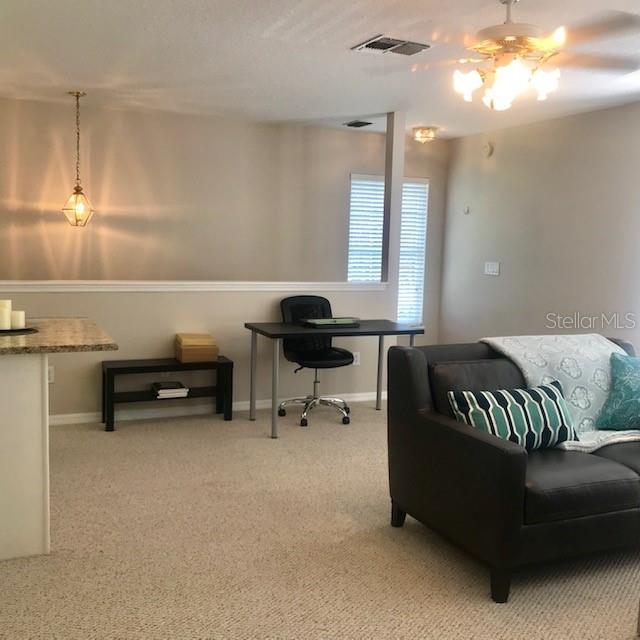 A living room features a desk, a dark armchair, and a kitchen counter — 533 GREENBRIER AVENUE UNIT B, CELEBRATION, FL