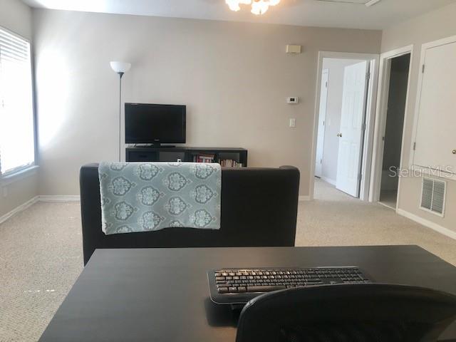 A view from a desk looking toward a television, a sofa, and two doorways — 533 GREENBRIER AVENUE UNIT B, CELEBRATION, FL