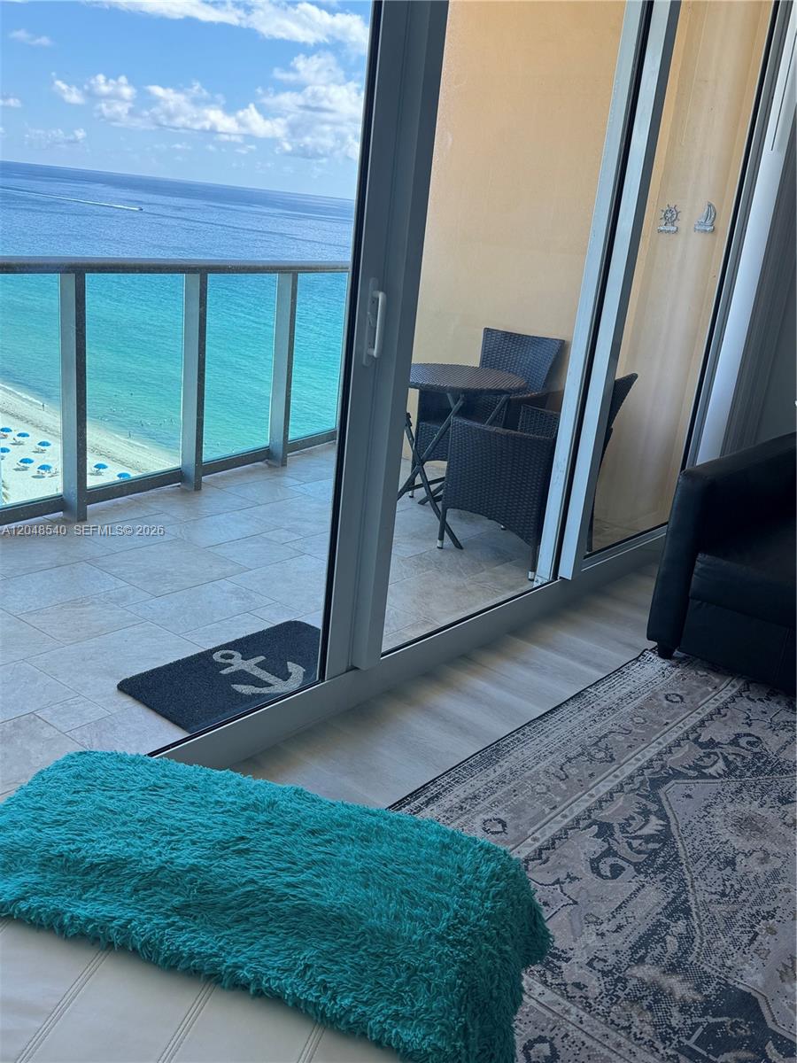 A balcony with a table and chairs overlooks the ocean through sliding glass doors — 2501 S Ocean Dr, Hollywood FL 33019, HOLLYWOOD, FL