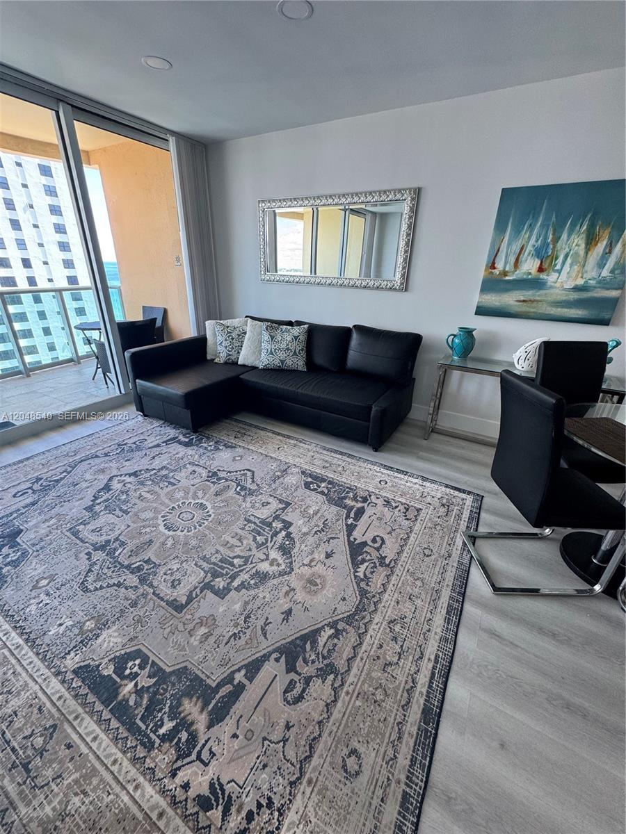 A living room features a black sectional sofa, a large patterned rug, and balcony access — 2501 S Ocean Dr, Hollywood FL 33019, HOLLYWOOD, FL