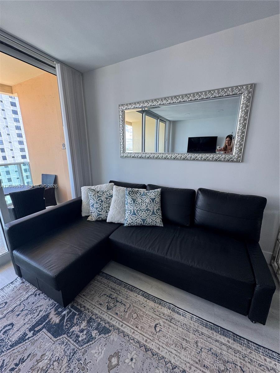 A black sectional sofa sits on a patterned rug beneath a large decorative wall mirror — 2501 S Ocean Dr, Hollywood FL 33019, HOLLYWOOD, FL