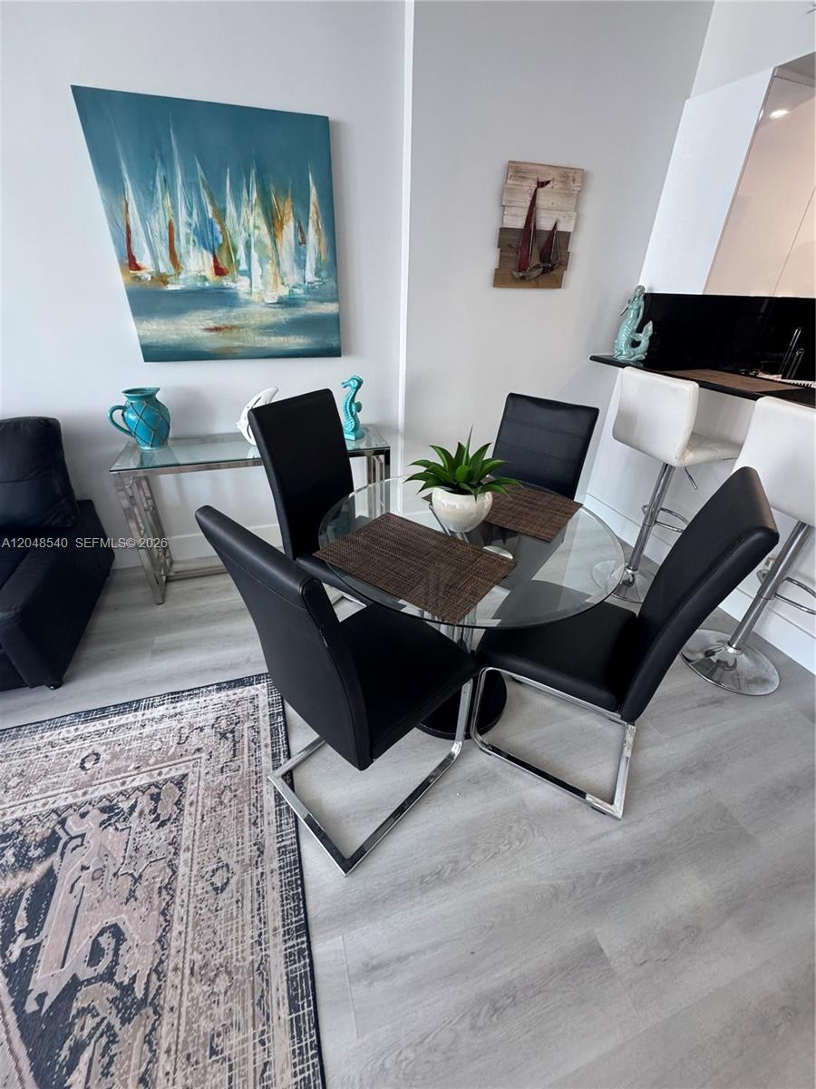 A dining area features a glass table with four black chairs and nautical-themed wall art — 2501 S Ocean Dr, Hollywood FL 33019, HOLLYWOOD, FL