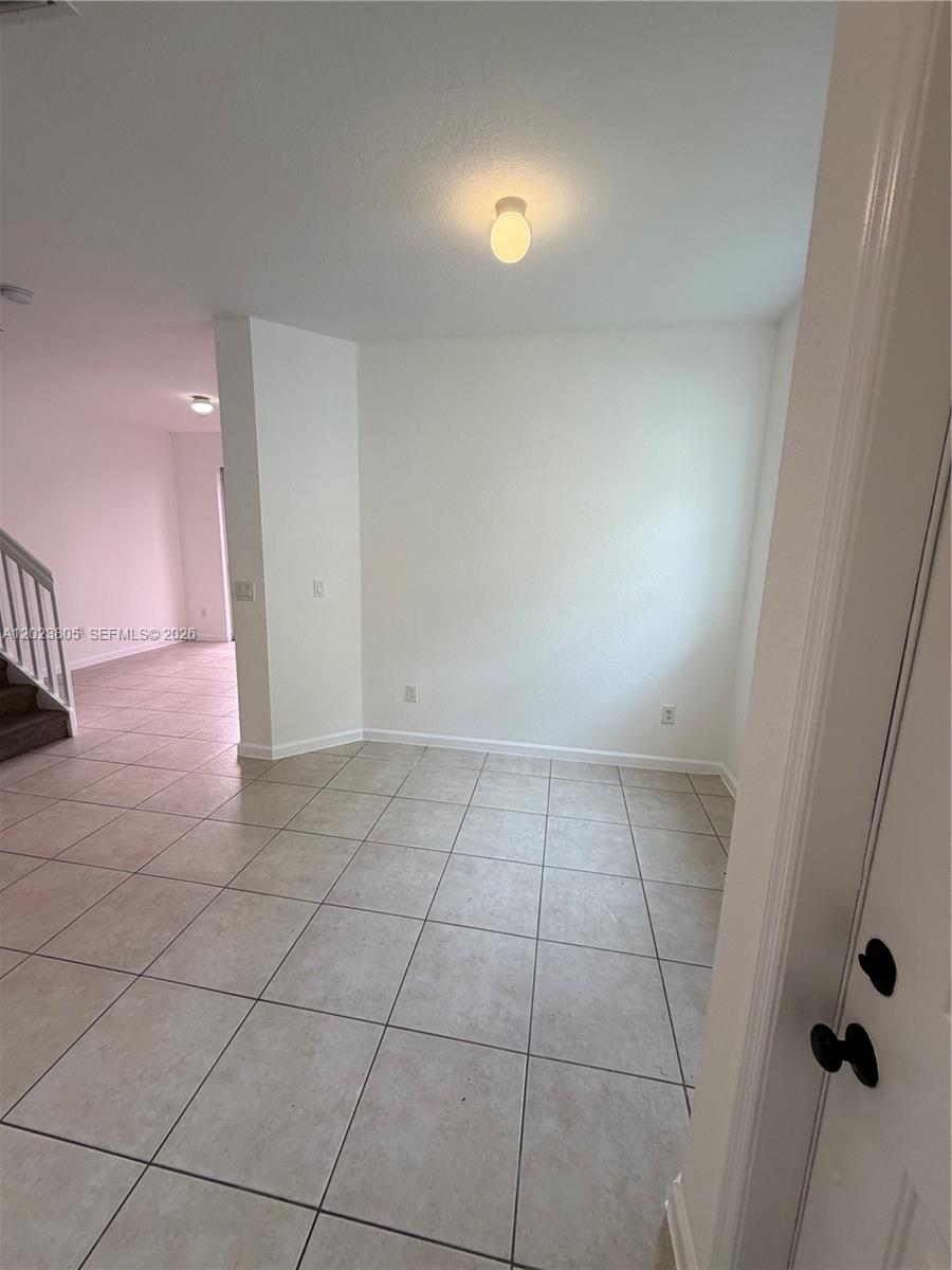 A room with light-colored tile flooring, white walls, and a ceiling light fixture — 607 NE 21st Ter, Homestead FL 33033, HOMESTEAD, FL