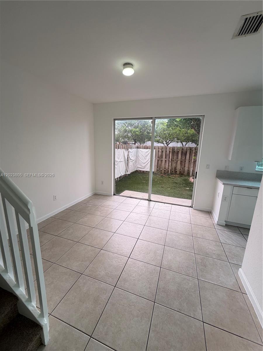 A tiled dining area features a sliding glass door opening to a fenced backyard — 607 NE 21st Ter, Homestead FL 33033, HOMESTEAD, FL