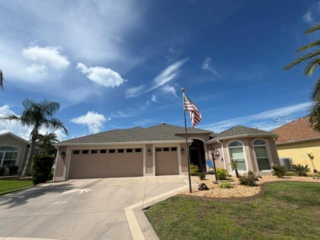 A single-story house with a three-car garage, a front lawn, and an American flag — 1448 GABLE PLACE, THE VILLAGES, FL