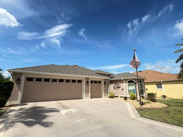 A single-story house with a large garage, a concrete driveway, and an American flag — 1448 GABLE PLACE, THE VILLAGES, FL