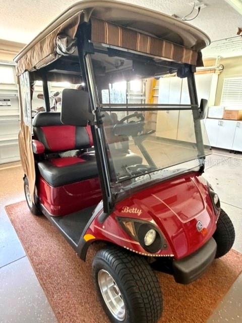 A red Yamaha golf cart named Betty is parked inside a garage — 1448 GABLE PLACE, THE VILLAGES, FL