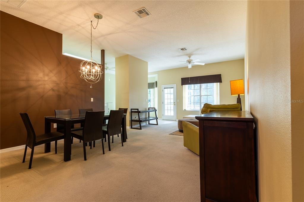 A dining area with a dark accent wall and chandelier opens into a living room — 7541 MOORGATE COURT, NEW PORT RICHEY, FL