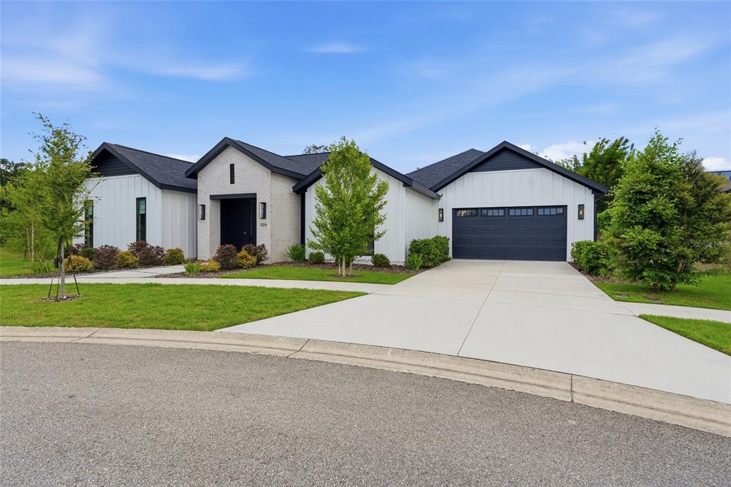 A modern house exterior features white vertical siding, a brick entryway, and a stone walkway — 1324 SW 120TH DRIVE, GAINESVILLE, FL