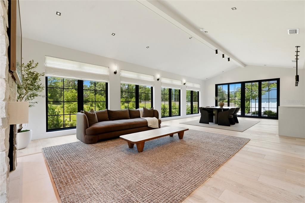 A bright living room features a stone fireplace, brown sofa, area rug, and large windows — 1324 SW 120TH DRIVE, GAINESVILLE, FL
