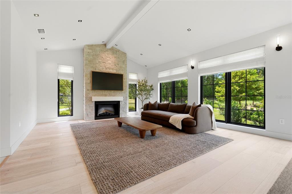 An open-concept kitchen and dining area features dark cabinetry, a large island, and stone fireplace — 1324 SW 120TH DRIVE, GAINESVILLE, FL
