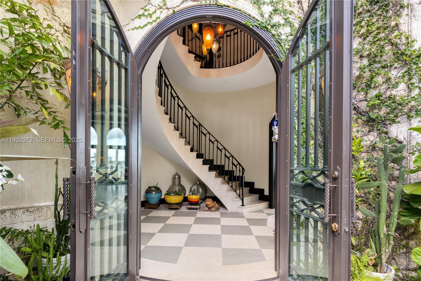 An arched doorway opens into a foyer featuring a curved staircase and checkered stone flooring — 10330 W Broadview Dr, Bay Harbor Islands FL 33154, BAY HARBOR ISLANDS, FL