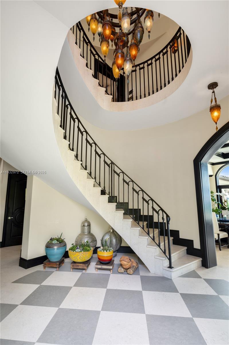 A curved staircase with a black iron railing sits above a checkered floor — 10330 W Broadview Dr, Bay Harbor Islands FL 33154, BAY HARBOR ISLANDS, FL