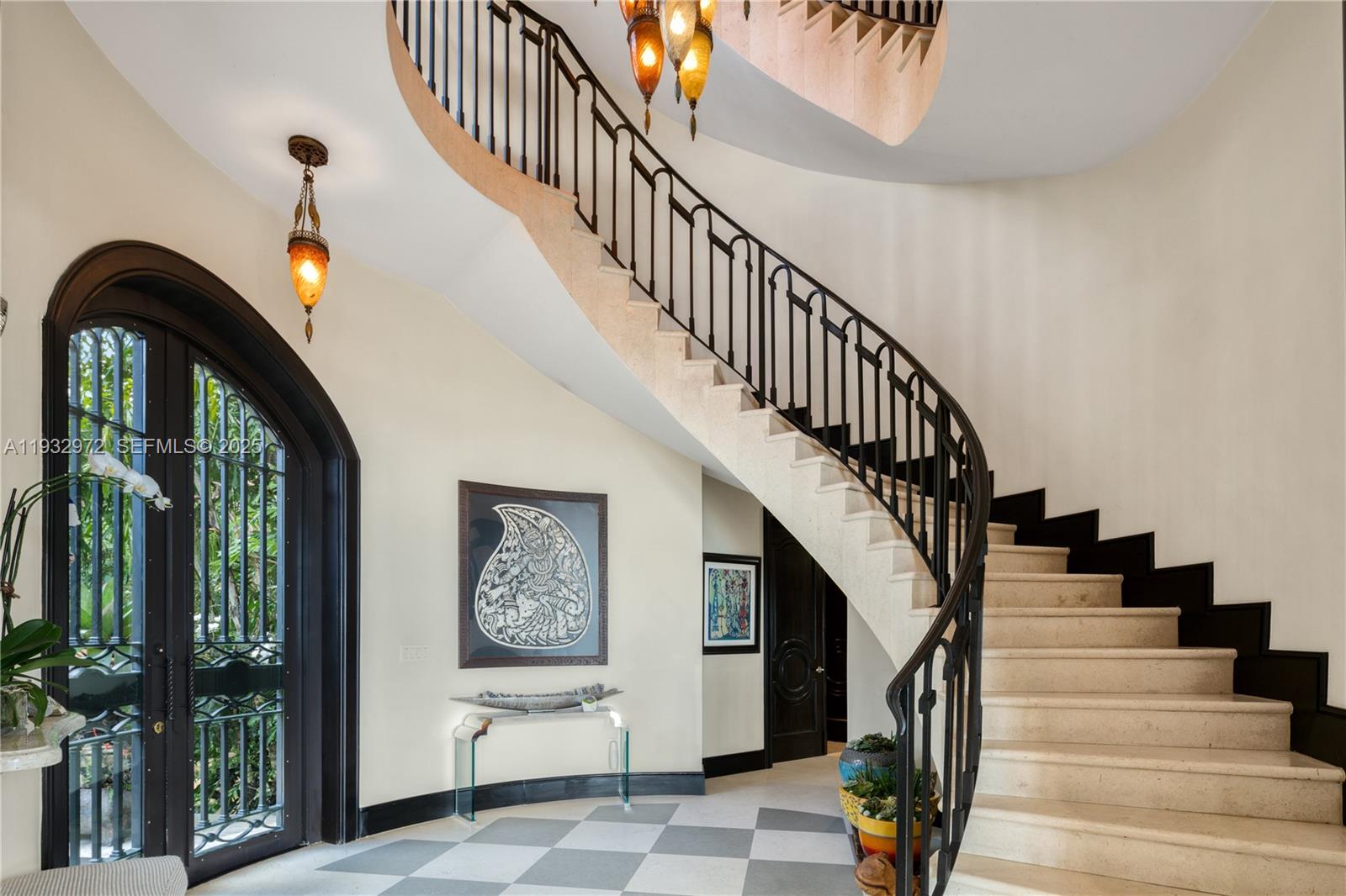 A grand foyer features a curved stone staircase, black iron railings, and checkered tile flooring — 10330 W Broadview Dr, Bay Harbor Islands FL 33154, BAY HARBOR ISLANDS, FL