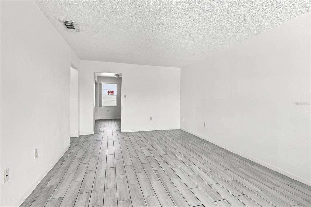 An empty room features white walls, a textured ceiling, and light gray wood-look tile flooring — 101 LAKE HUNTER DRIVE UNIT 11, LAKELAND, FL