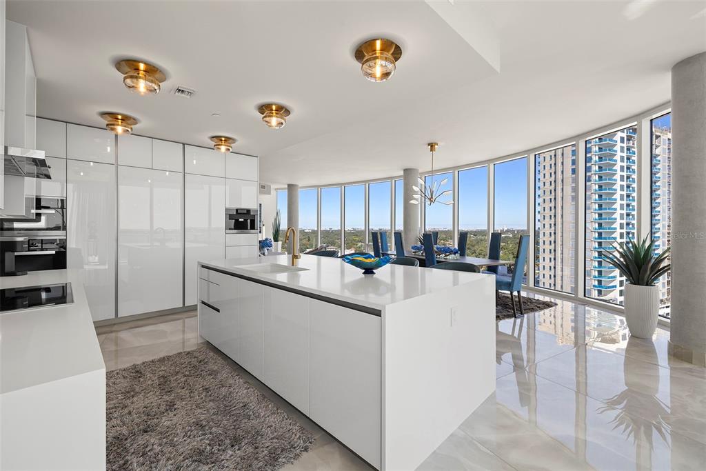 A modern kitchen with white cabinetry and a large island overlooks a city skyline view — 2900 W BAY TO BAY BOULEVARD UNIT 1403, TAMPA, FL