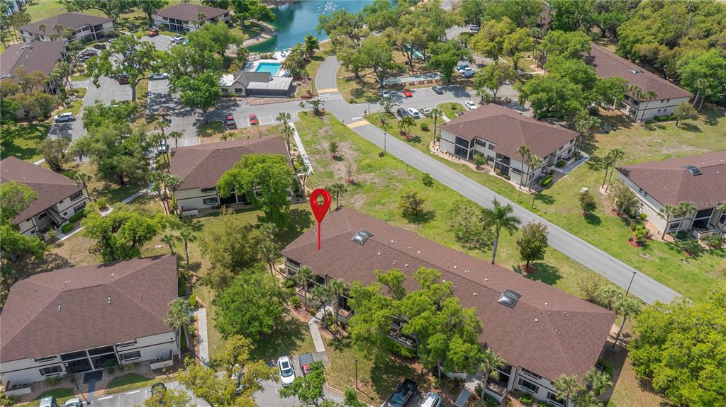 An aerial view shows a multi-story apartment building with a brown roof and surrounding landscaping — 19505 QUESADA AVENUE UNIT O207, PORT CHARLOTTE, FL