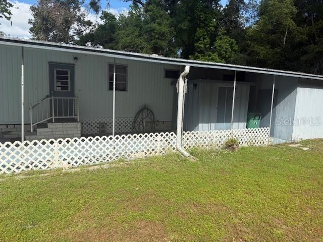 The exterior of a mobile home features a covered carport, lattice skirting, and a storage shed — 7256 WINDY WAY, BROOKSVILLE, FL