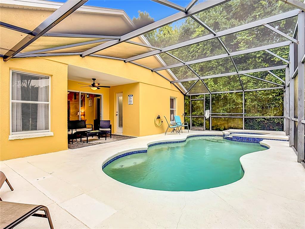A yellow house features a screened-in patio with a swimming pool and attached spa — 522 SANDY RIDGE DRIVE, DAVENPORT, FL