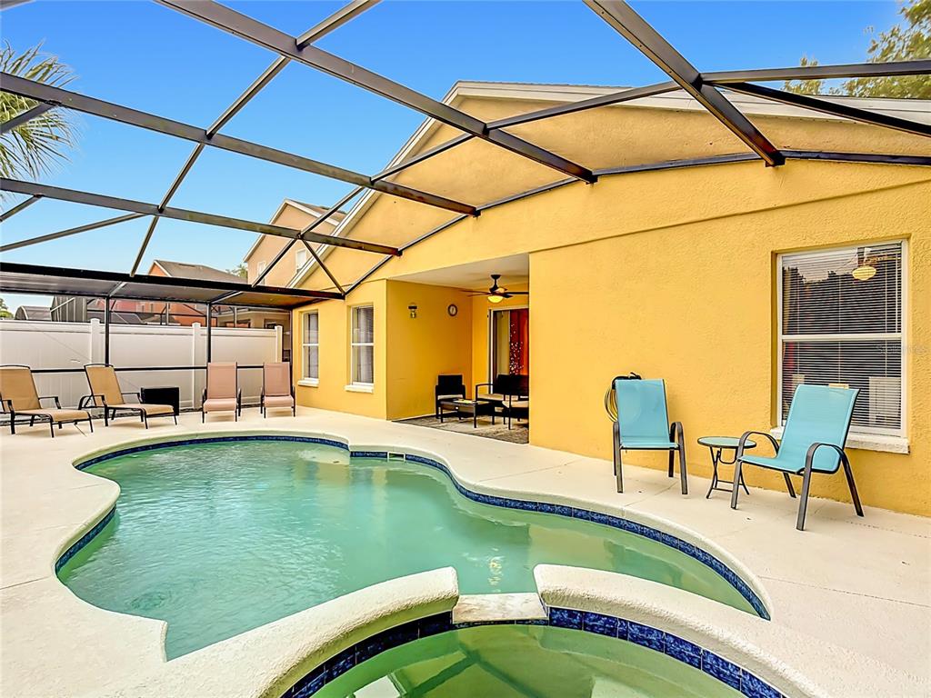 A swimming pool and hot tub sit on a patio enclosed by a screened lanai — 522 SANDY RIDGE DRIVE, DAVENPORT, FL