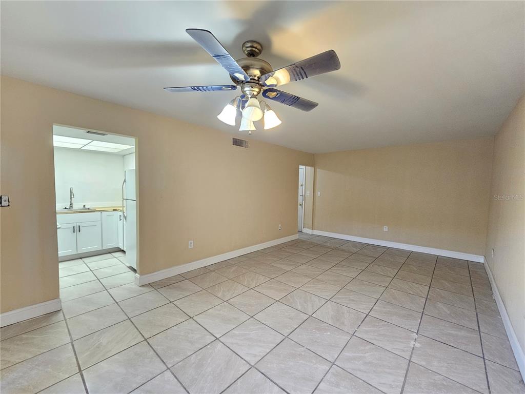 A living area with beige walls, tile flooring, and a ceiling fan, adjacent to a kitchen — 7601 PAULA DRIVE UNIT 3, TAMPA, FL
