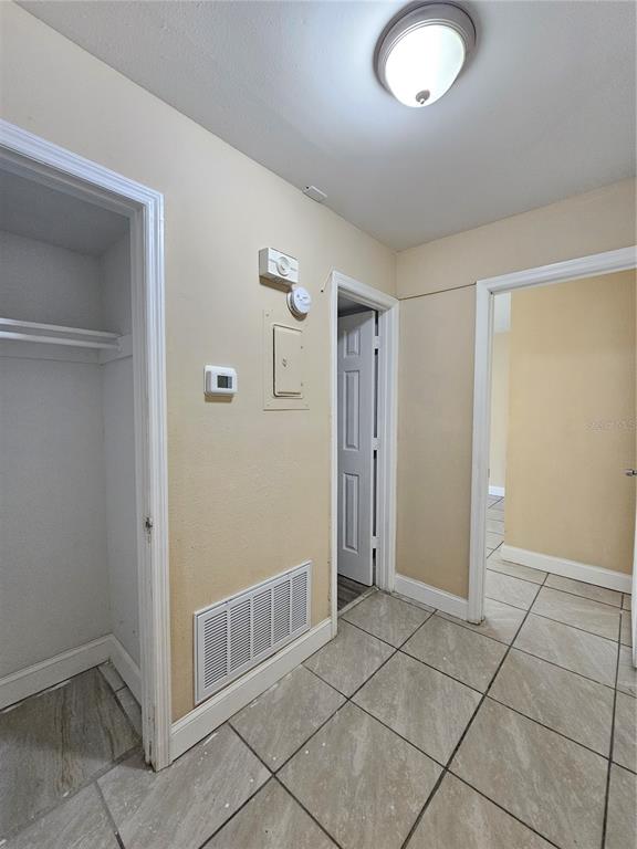 A hallway with tiled floors, a closet, two doorways, and wall-mounted utility controls — 7601 PAULA DRIVE UNIT 3, TAMPA, FL