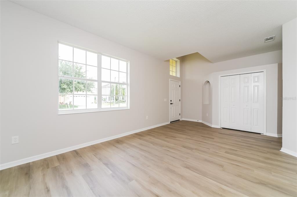 An empty room with light wood-look flooring, a large window, and white closet doors — 539 BRENTFORD COURT, KISSIMMEE, FL