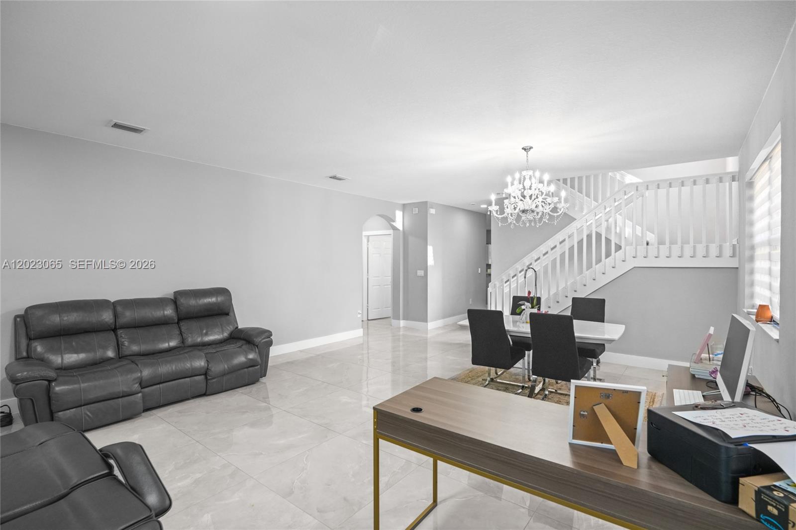 This open-concept living and dining area features light tile flooring, a staircase, and modern furniture — 11711 SW 234th St, Homestead FL 33032, HOMESTEAD, FL