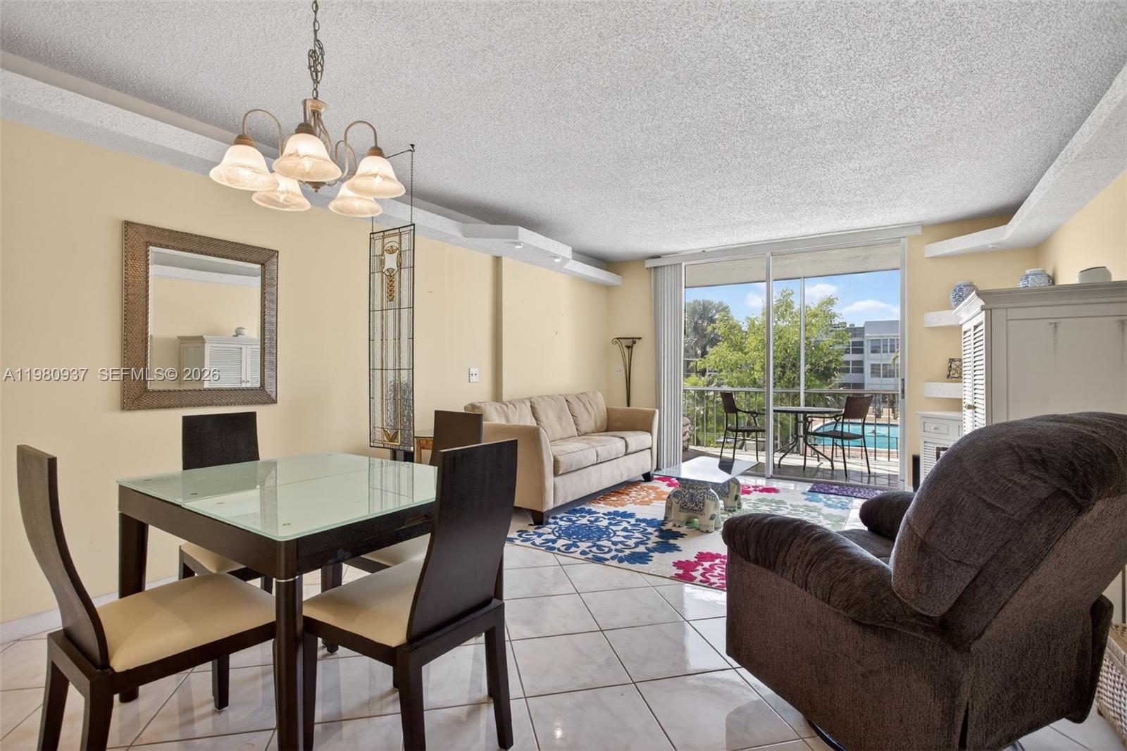 A living and dining area features tile floors, a glass-top table, and a balcony view — 6600 Royal Palm Blvd # 207B, Margate FL 33063, MARGATE, FL