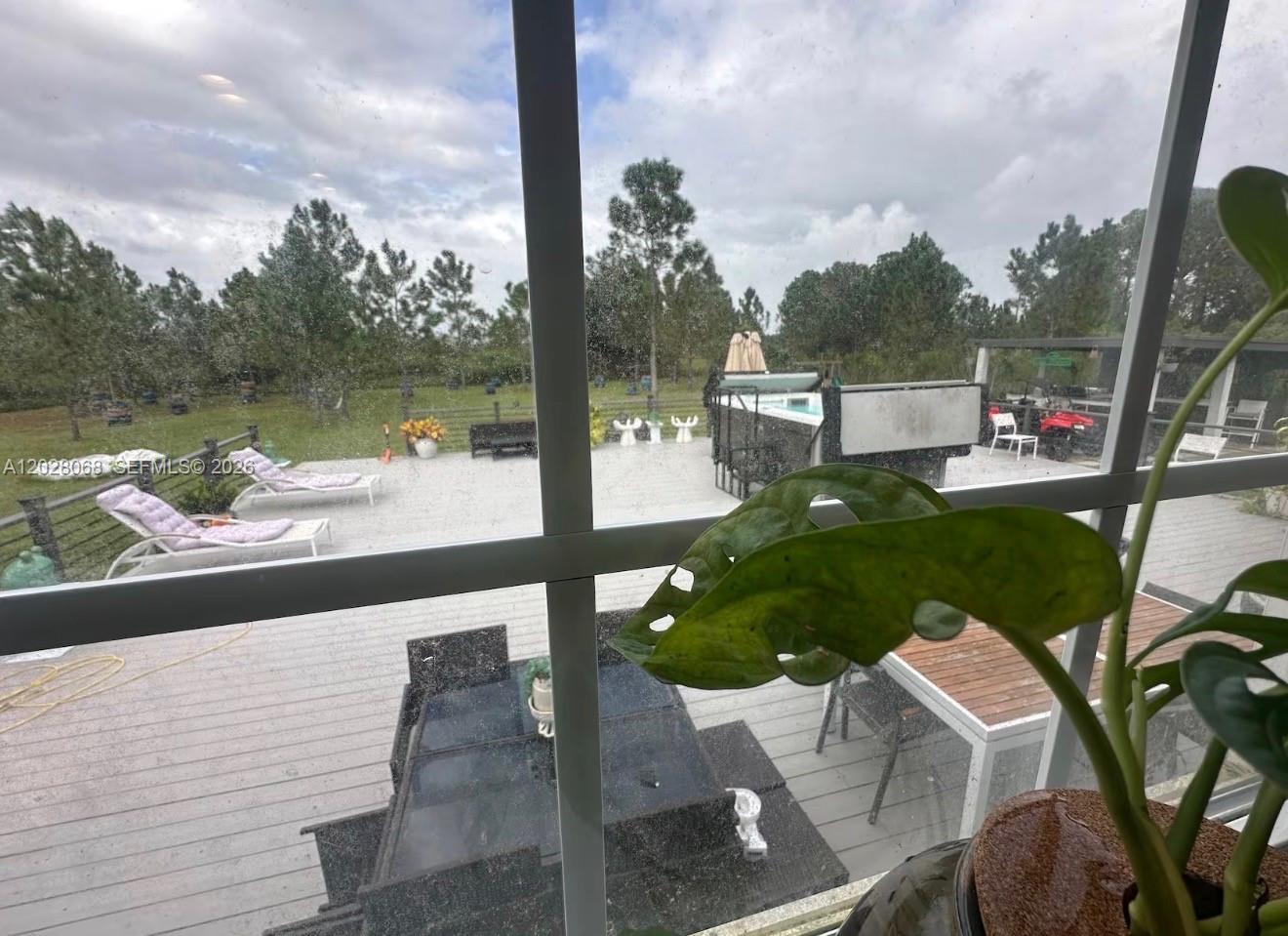 A view through a window shows a deck with lounge chairs, a hot tub, and furniture — 17663 NW 266TH ST, Okeechobee FL 34972, OKEECHOBEE, FL