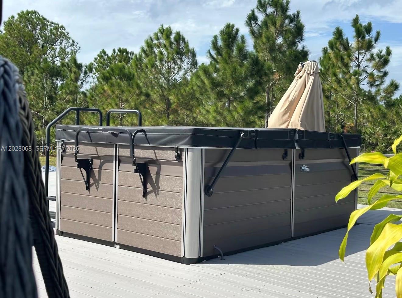 A rectangular hot tub with a black cover sits on a wooden deck outdoors — 17663 NW 266TH ST, Okeechobee FL 34972, OKEECHOBEE, FL