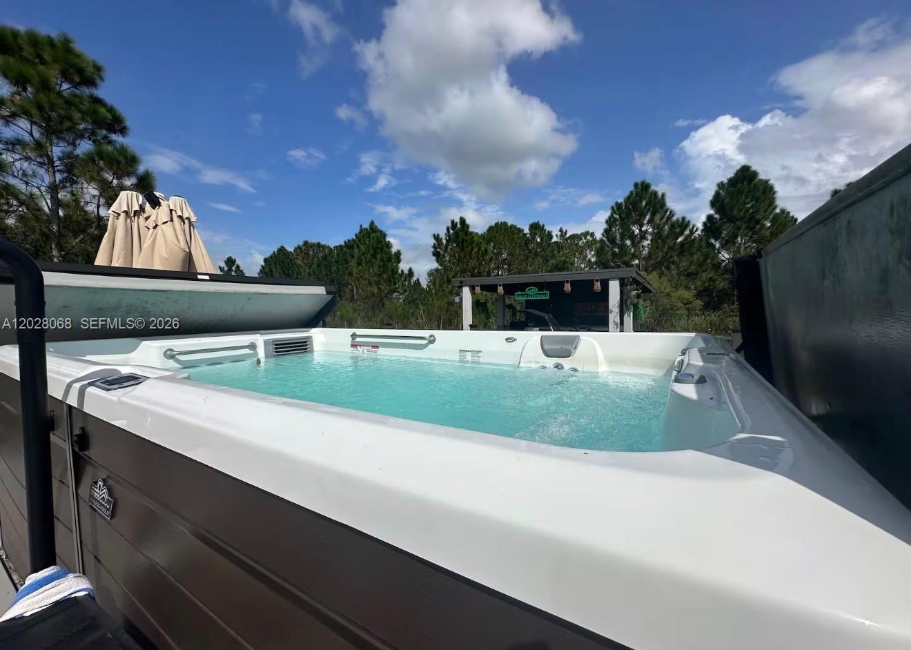 An outdoor swim spa with a dark wood-paneled exterior sits under a blue sky — 17663 NW 266TH ST, Okeechobee FL 34972, OKEECHOBEE, FL
