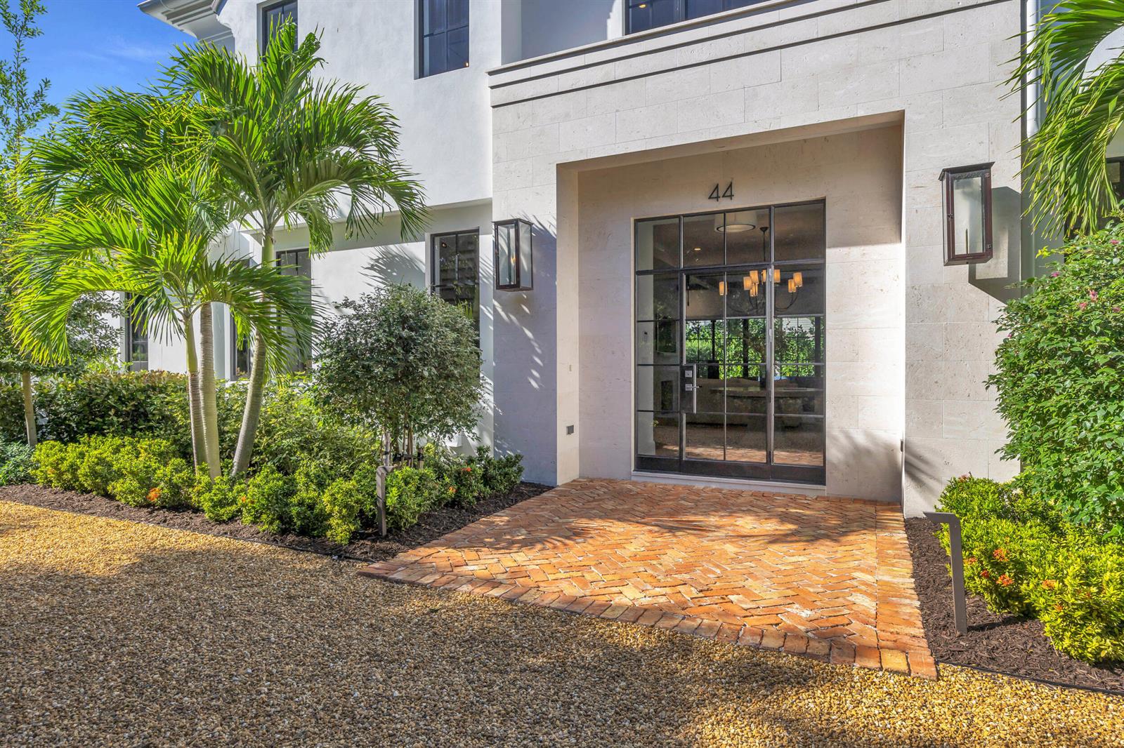 The exterior of a white house features a brick entryway and a glass-paned front door — 44 S Beach Road, Jupiter Island FL 33455, JUPITER ISLAND, FL