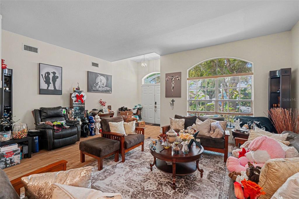 A living room with tile floors, a large arched window, and various furniture and decor — 7212 HAMMET ROAD, TAMPA, FL
