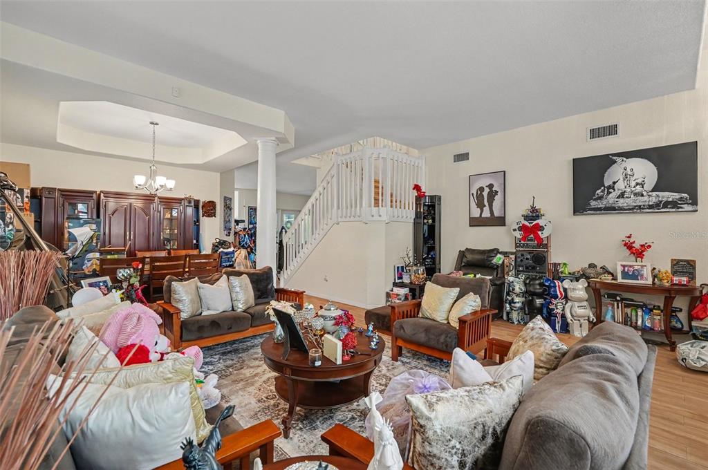 A living room with wooden furniture, a central staircase, and a dining area in back — 7212 HAMMET ROAD, TAMPA, FL