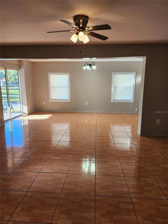 An empty room features glossy wood-look tile flooring, a ceiling fan, and two windows — 2220 BIRCHCREST BOULEVARD, PORT CHARLOTTE, FL